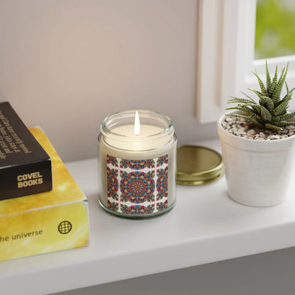 An Aromatherapy Candle Essential Oil from Printify, housed in a glass jar adorned with a colorful geometric design, rests on a white shelf. It infuses the room with its zen candle benefits. Next to it are two stacked books and a small potted succulent, creating an airy ambiance against the window backdrop.