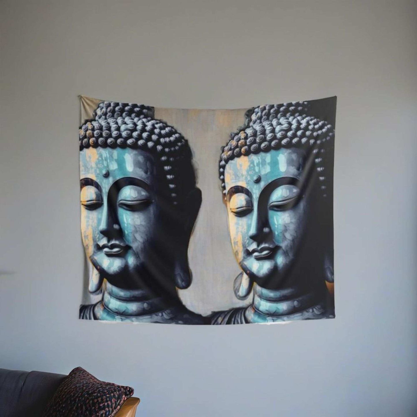 The Blue Buddha Indoor Wall Tapestry by Printify, featuring two serene blue Buddha head statues on a light background, brings tranquility to any room. This Zen tapestry is displayed on a simple wall above a sofa adorned with patterned cushions, making it an ideal addition to meditation spaces.