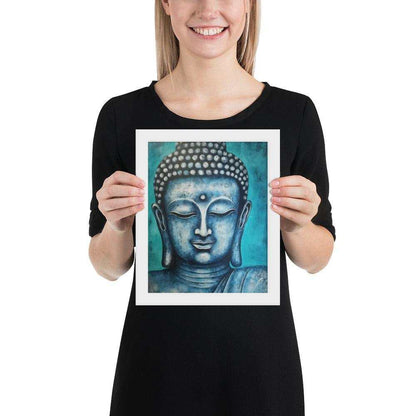 A woman with a bright smile is holding a white oak framed poster depicting a serene blue Buddha head against a textured teal background, blending spiritual calm with rich, modern colors.