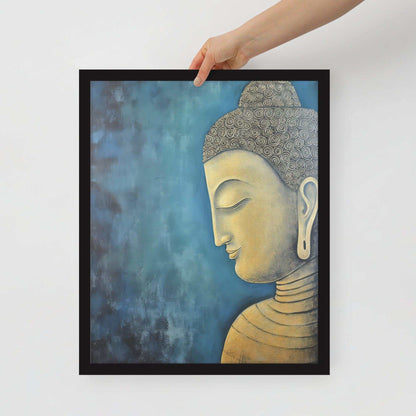 A hand is placing a framed poster on a white background, where a serene Golden Buddha Art with a patterned head and golden features is portrayed in profile against a mottled blue backdrop, all within a black oak frame.