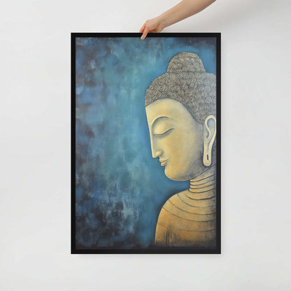 A hand is placing a framed poster on a white background, where a serene Golden Buddha Art with a patterned head and golden features is portrayed in profile against a mottled blue backdrop, all within a black oak frame.