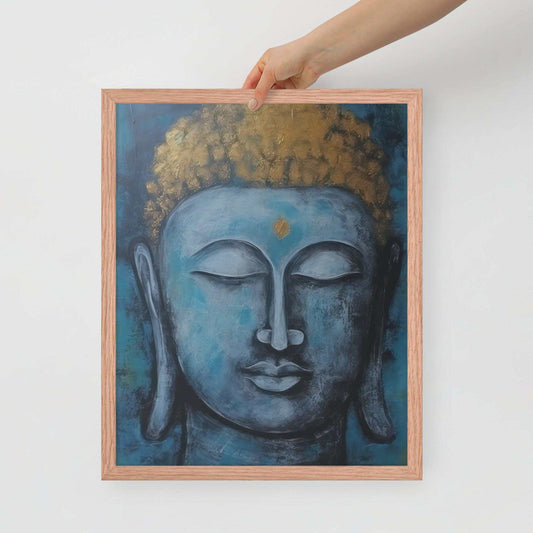 A hand is adjusting a framed poster with a red oak finish depicting a blue Buddha head with a textured gold leaf crown against a blue background, giving the impression of tranquility and artistic simplicity against a white backdrop.