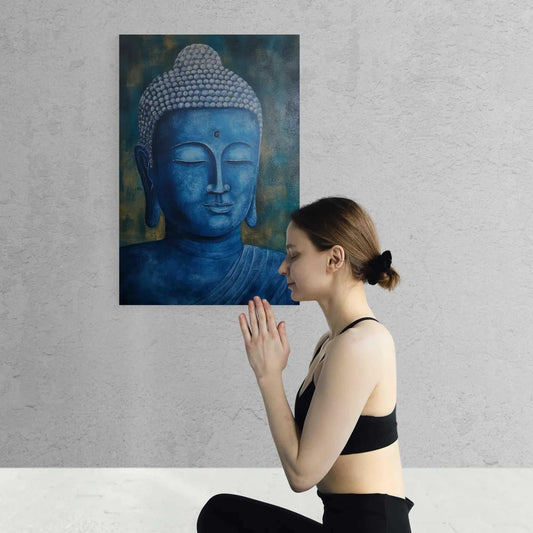 A woman in a black sports top and leggings sits in a meditative pose, with her hands pressed together in front of a blue and gold Buddha painting.