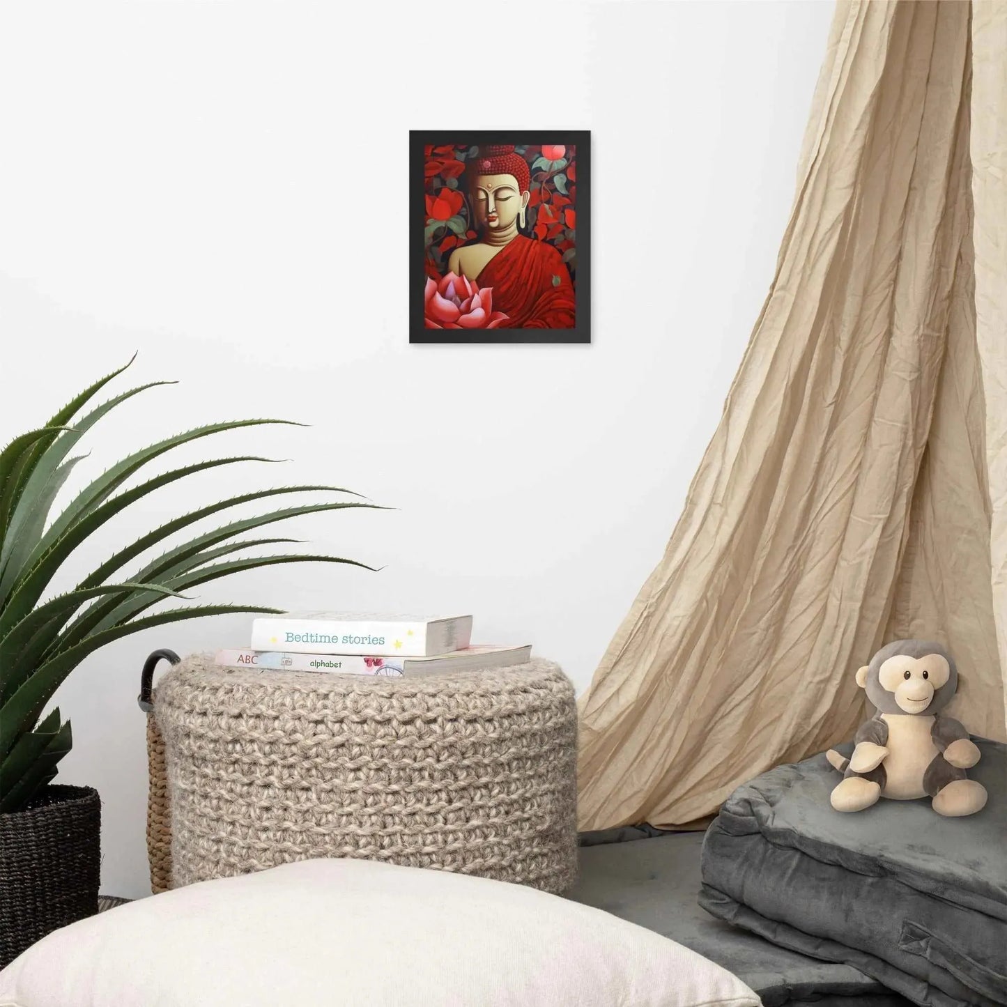 A framed poster of a red Buddha in meditation with a radiant red aura and a large pink lotus flower is set against a backdrop of dark red leaves, creating a peaceful corner in a room with a cozy reading nook, complete with cushions, a woven pouf, and a soft curtain. Nearby, a plush toy monkey adds a touch of playfulness to the tranquil setting.