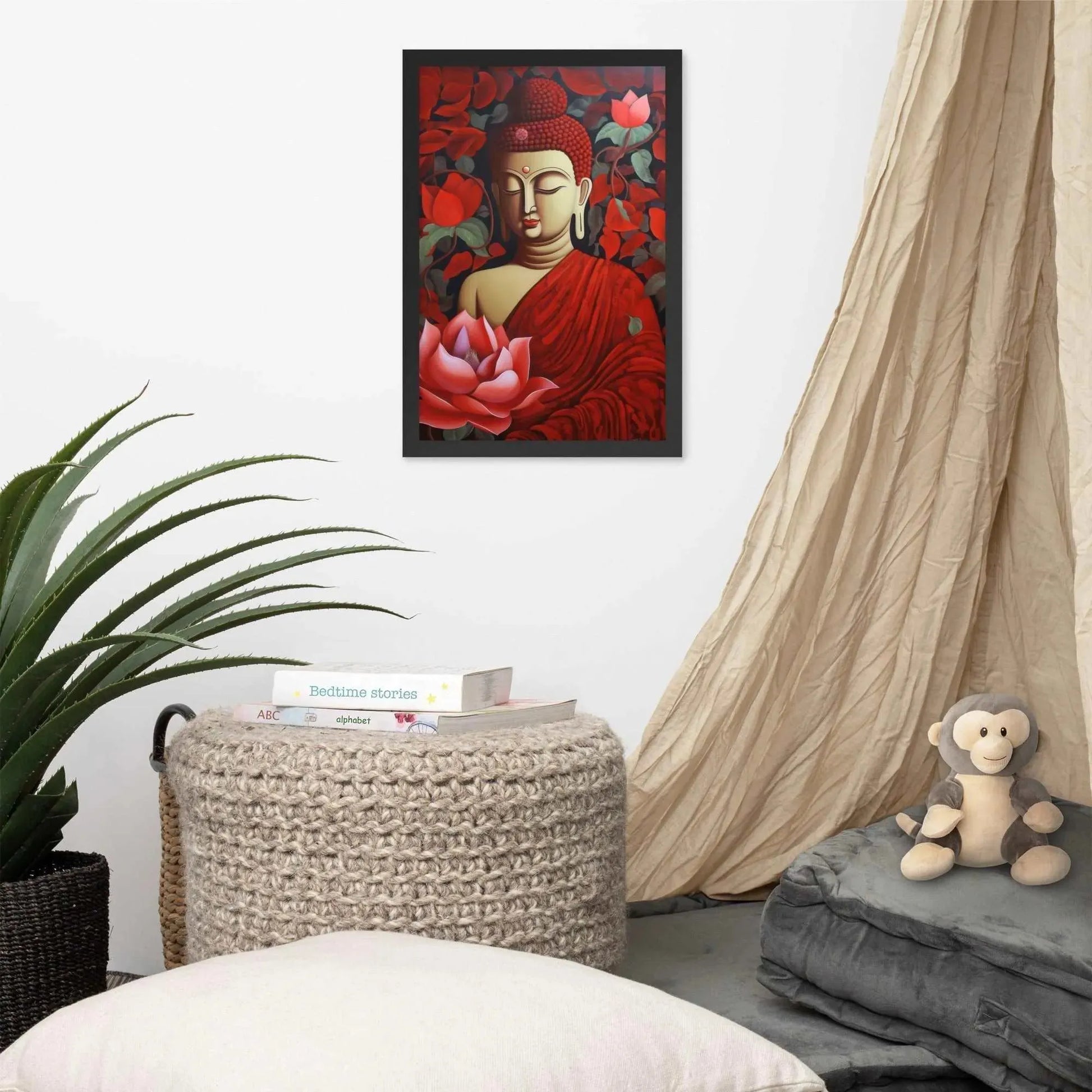 A framed poster of a red Buddha in meditation with a radiant red aura and a large pink lotus flower is set against a backdrop of dark red leaves, creating a peaceful corner in a room with a cozy reading nook, complete with cushions, a woven pouf, and a soft curtain. Nearby, a plush toy monkey adds a touch of playfulness to the tranquil setting.