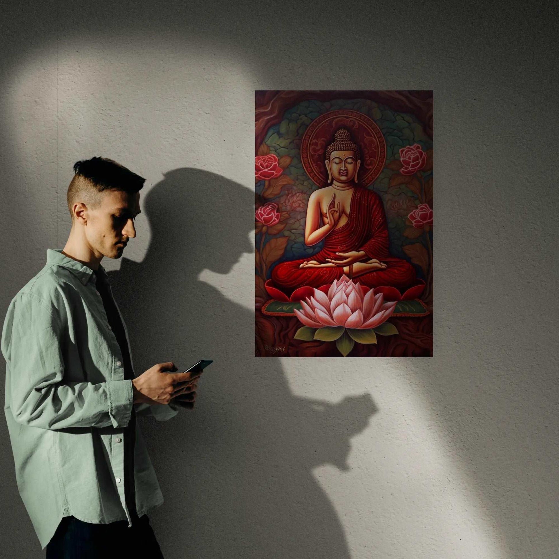 A person gazes at their phone beside a wall adorned with a seated Buddha painting in red and gold, showcasing a meditative Buddha over a blooming lotus, blending spirituality with modern life.