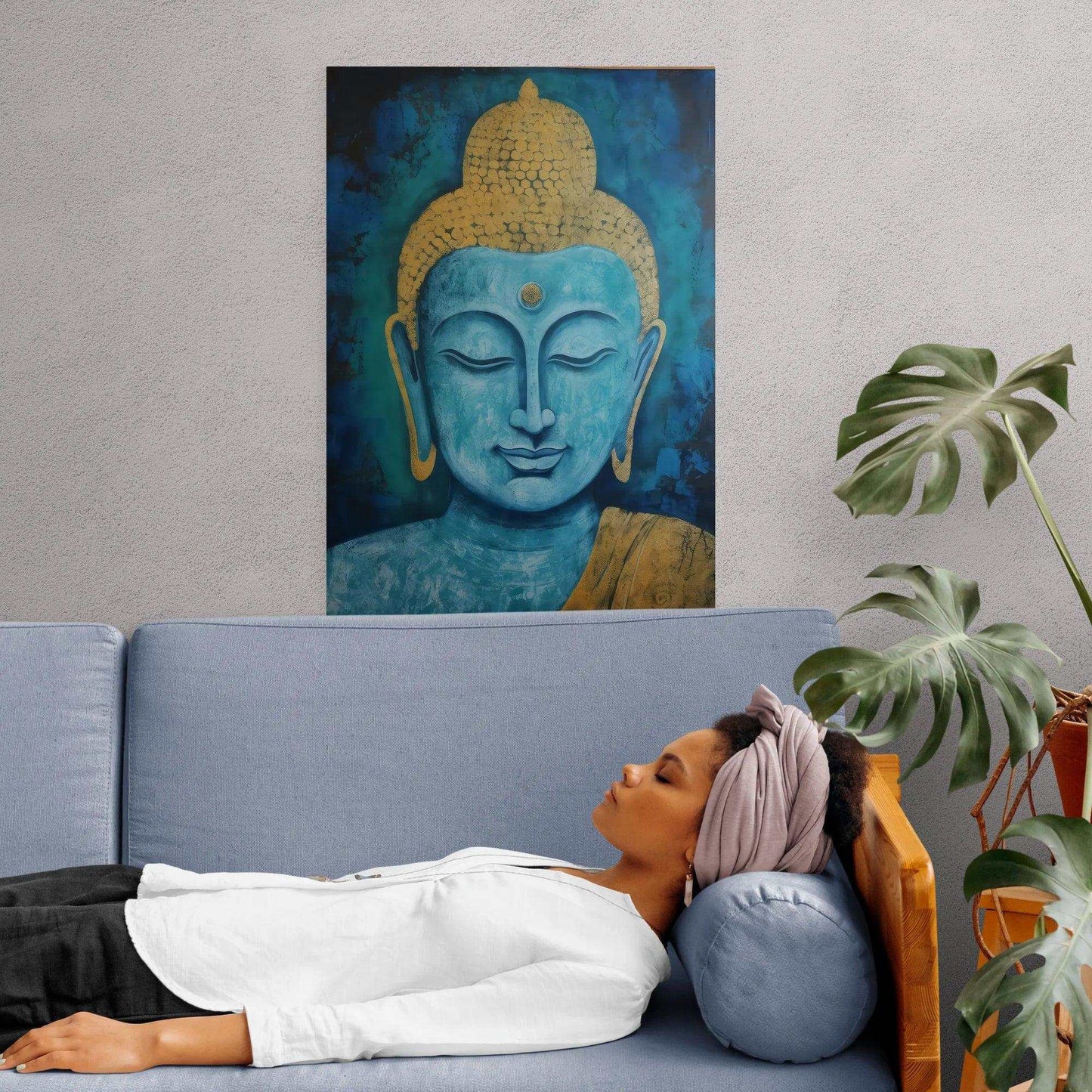 Relaxing living space with a woman reclining on a light grey couch, a serene blue and gold Buddha artwork hanging above, adding a tranquil ambiance next to an indoor plant, conveying a sense of peace and meditation.