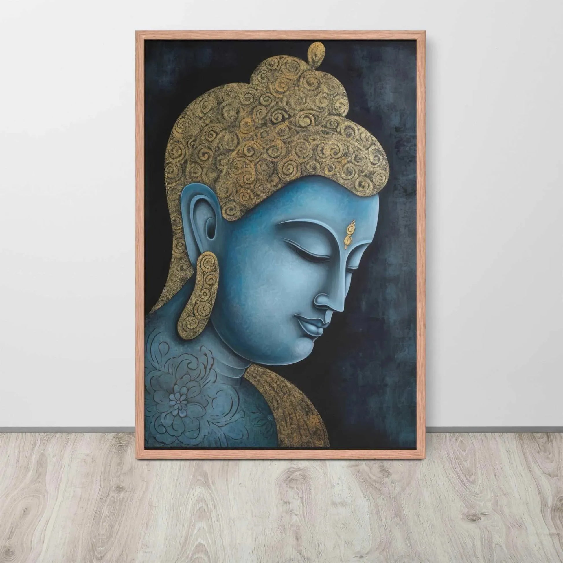 A framed Tibetan Blue Buddha Painting depicts a side profile of a serene, blue-toned Buddha with a golden patterned head, highlighted with a delicate golden ornament on the forehead. The artwork is placed against a dark, smokey background within a red oak frame, resting on a light wooden floor next to a white wall.