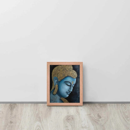 A framed Tibetan Blue Buddha Painting depicts a side profile of a serene, blue-toned Buddha with a golden patterned head, highlighted with a delicate golden ornament on the forehead. The artwork is placed against a dark, smokey background within a red oak frame, resting on a light wooden floor next to a white wall.