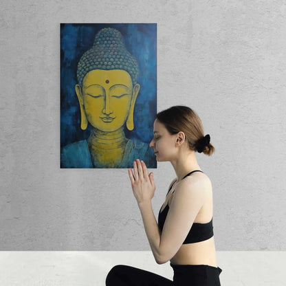 Woman in a black top practicing yoga with palms pressed together in namaste, facing a blue and gold Buddha head painting on a textured wall.