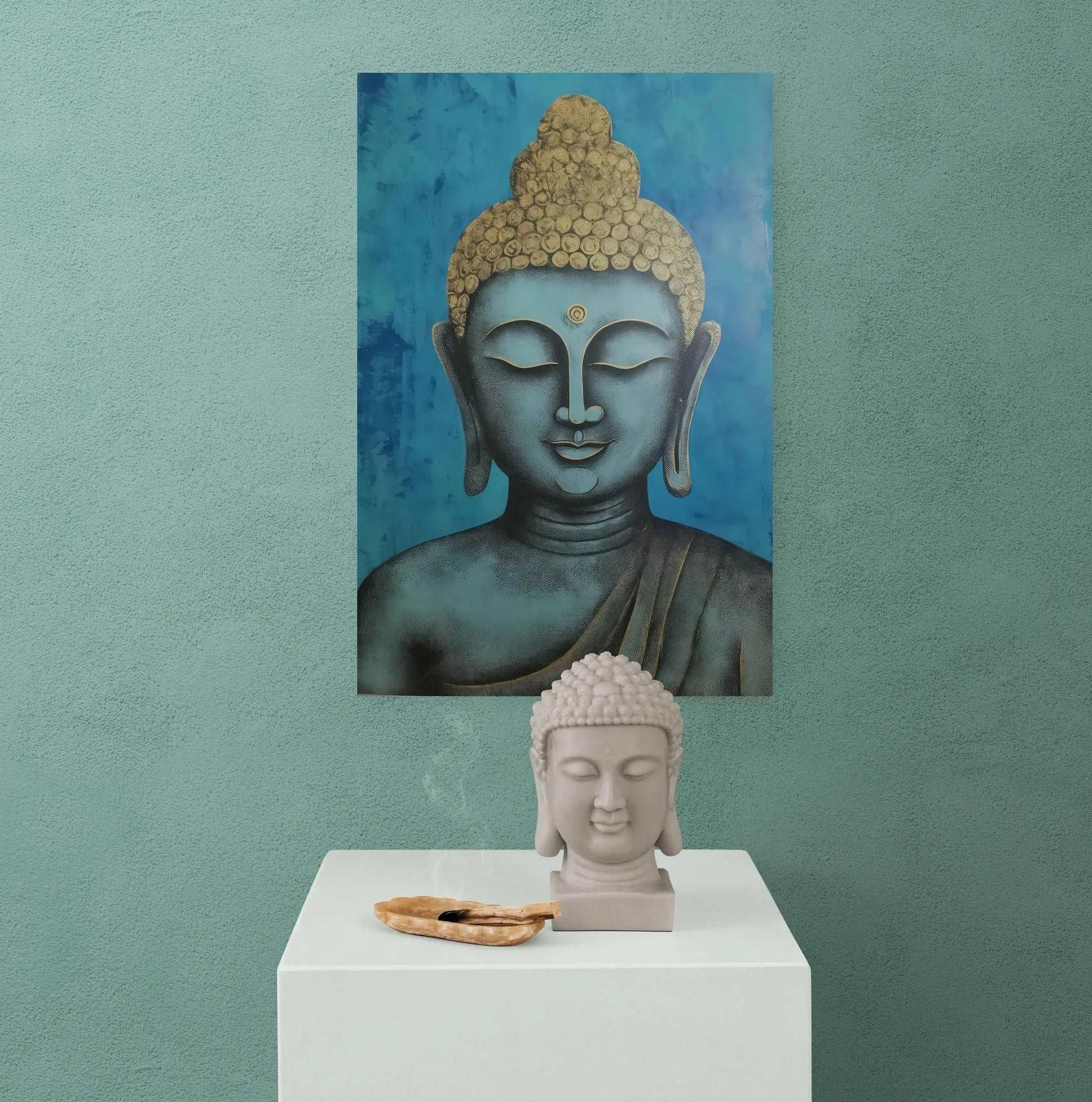 Buddha head statue on a white pedestal with palo santo sticks, against a teal wall with a blue and gold Buddha head painting.