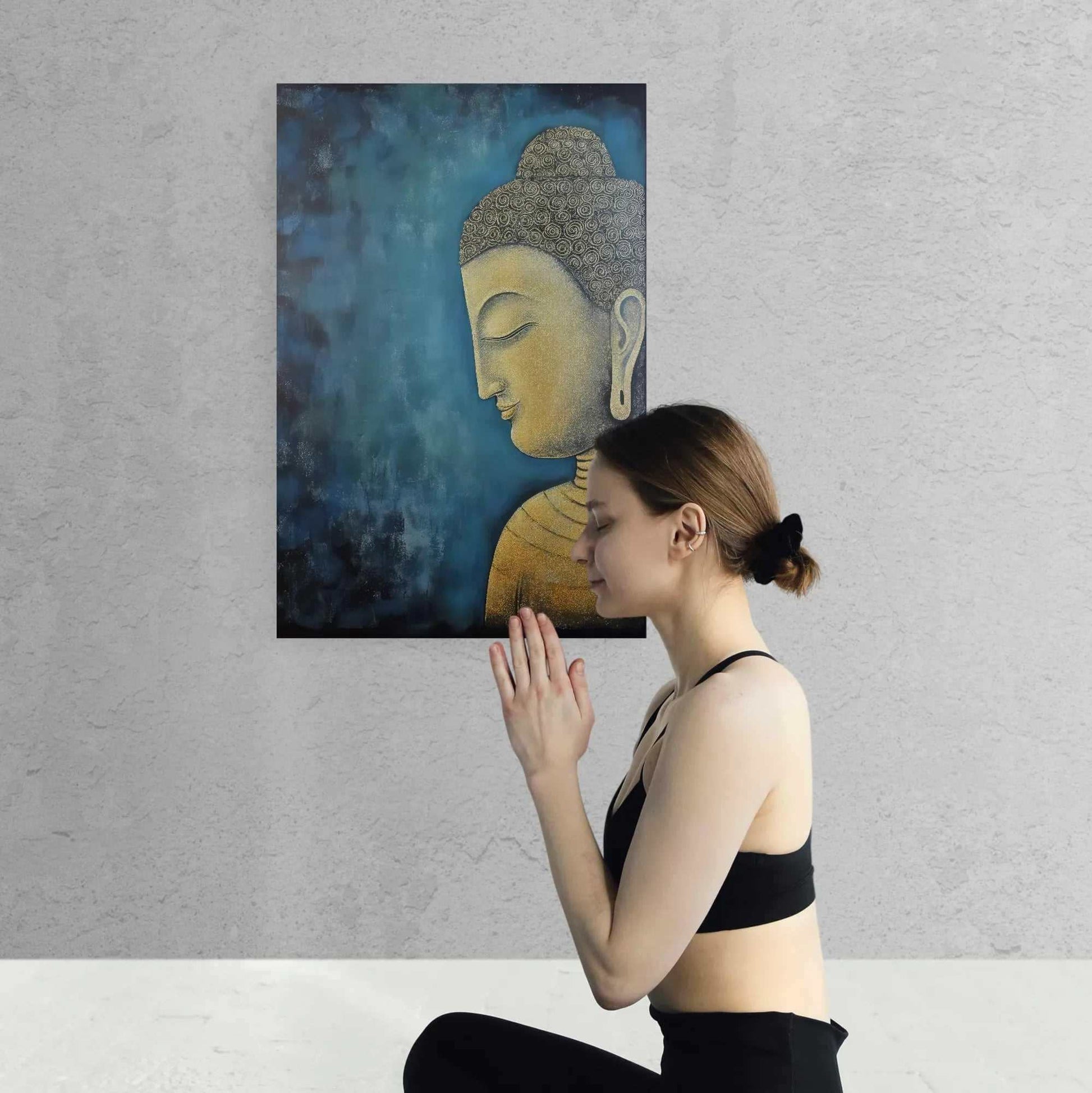 Young woman in black sportswear practicing meditation in front of a textured Buddha painting with gold and blue hues.