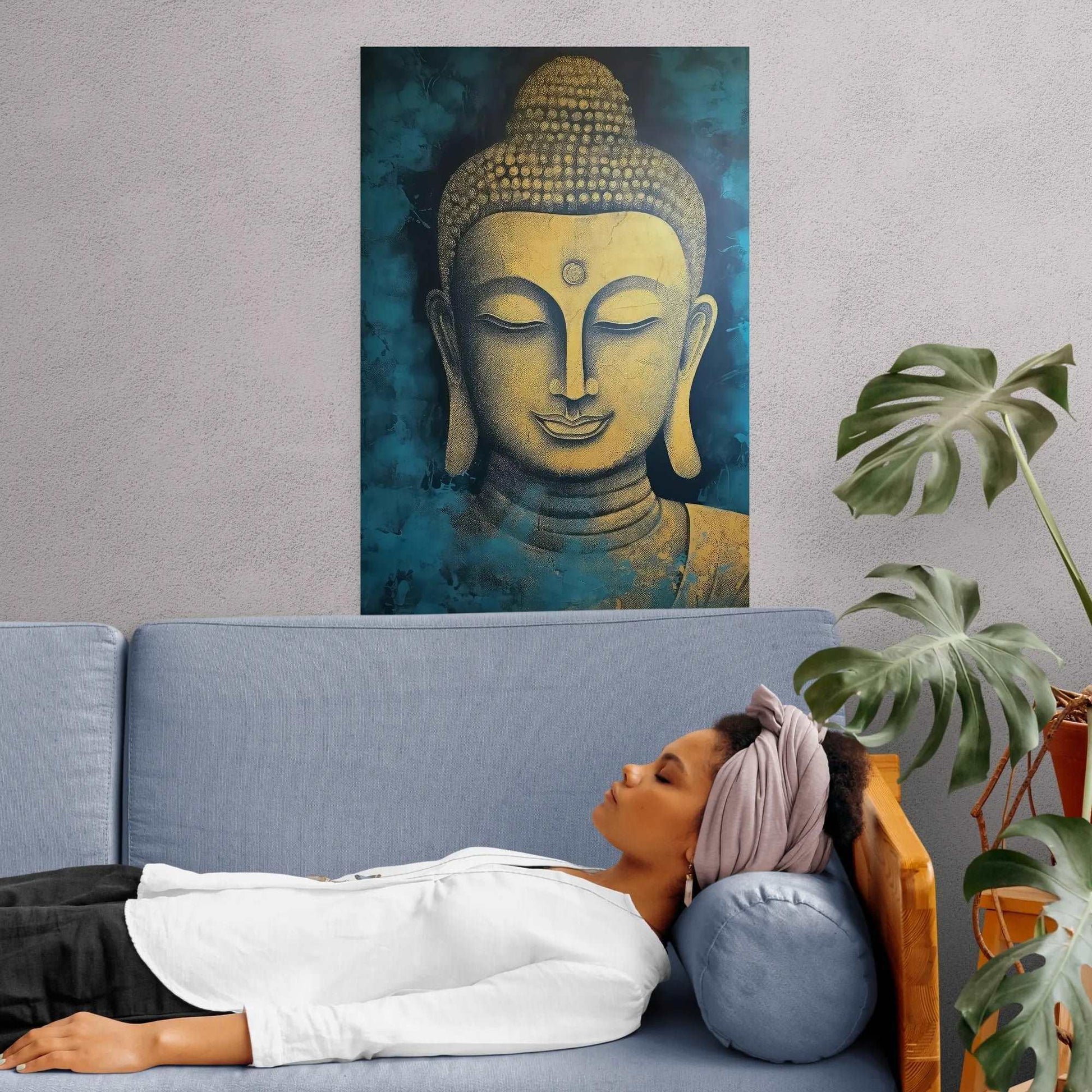 Woman lying on a blue couch with her head resting on a round pillow, underneath a golden Buddha head wall art, next to a monstera plant.